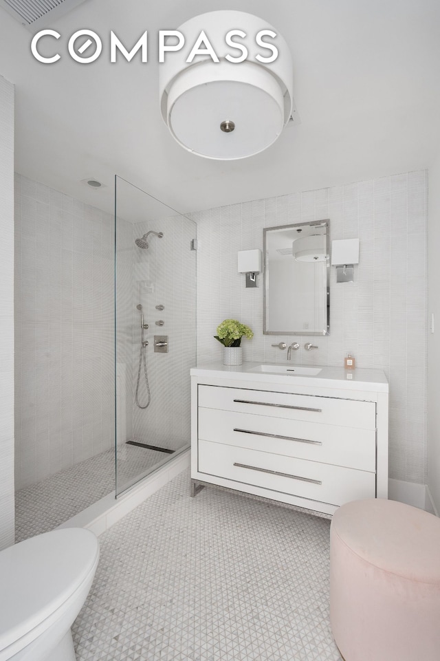 full bathroom with toilet, walk in shower, tile walls, and vanity