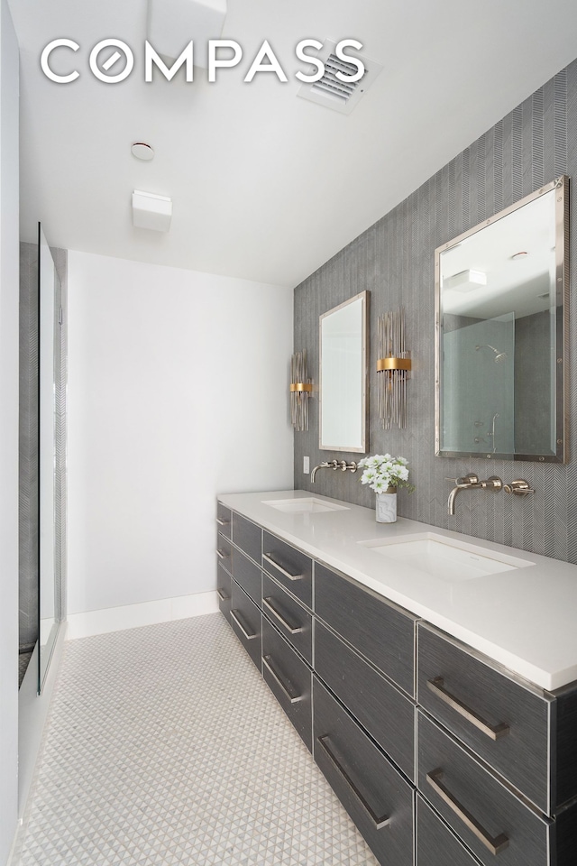 bathroom featuring double vanity, a sink, baseboards, and a shower
