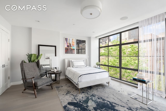 bedroom featuring baseboards, wood finished floors, and multiple windows