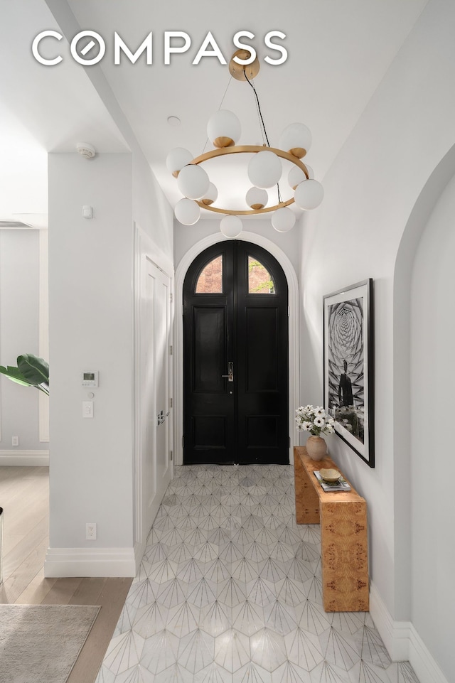 foyer featuring baseboards and arched walkways