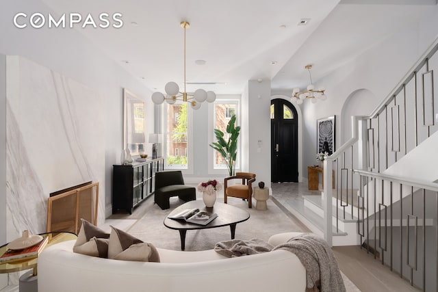 living area featuring an inviting chandelier, visible vents, and stairway