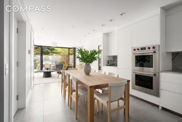 dining area featuring light tile patterned floors, expansive windows, and visible vents