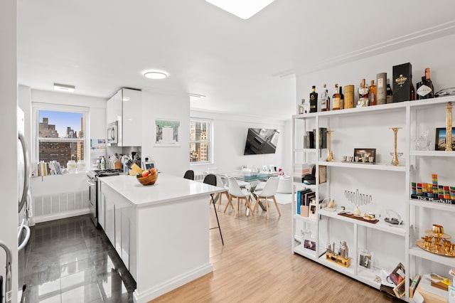 kitchen featuring a peninsula, modern cabinets, a kitchen breakfast bar, white cabinets, and appliances with stainless steel finishes