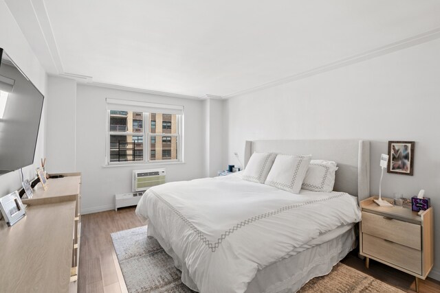 340 E 80th St Unit 17-D, New York City, NY 10075 - bedroom featuring a wall unit AC, wood finished floors, baseboard heating, and baseboards