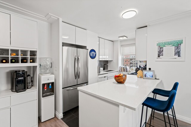 340 E 80th St Unit 17-D, New York City, NY 10075 - kitchen featuring stainless steel fridge, a kitchen bar, a peninsula, white cabinets, and modern cabinets