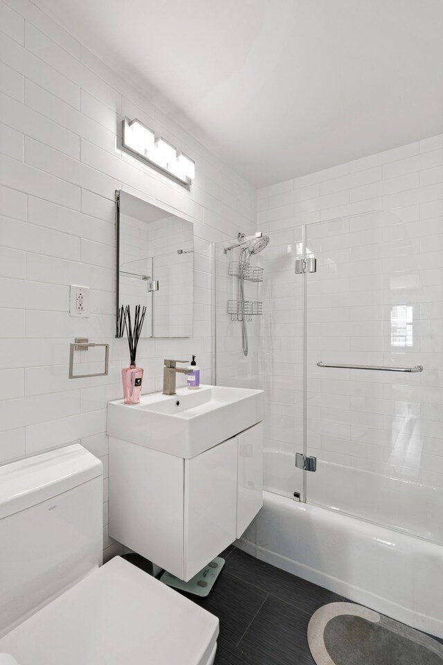 340 E 80th St Unit 17-D, New York City, NY 10075 - bathroom with toilet, vanity, shower / bath combination with glass door, and tile walls