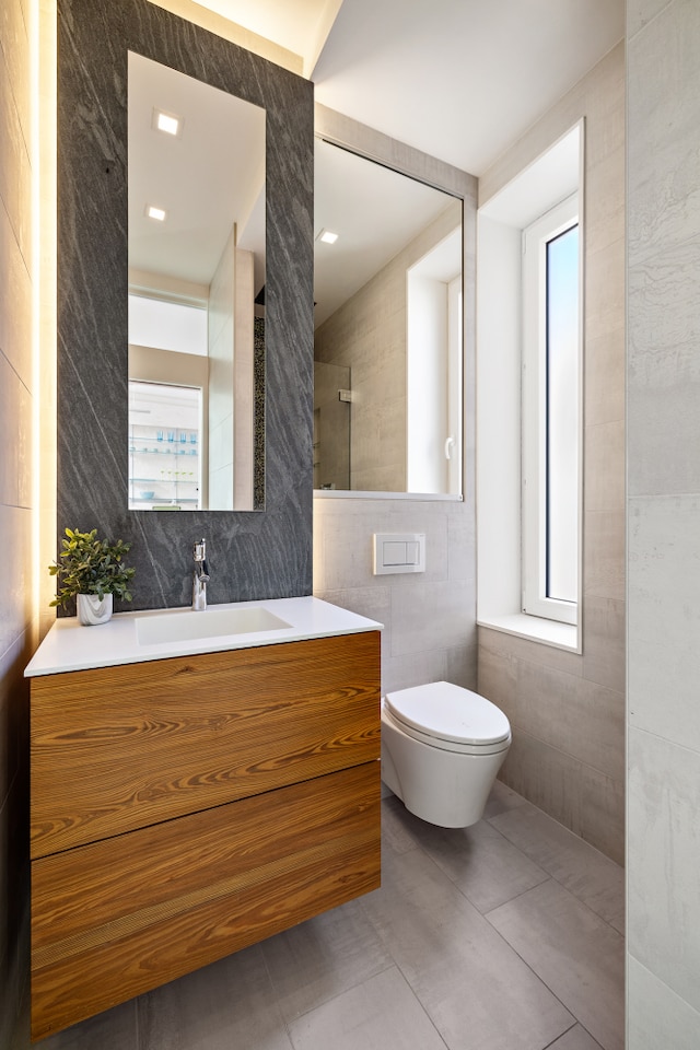 bathroom featuring a healthy amount of sunlight, tile walls, vanity, and toilet