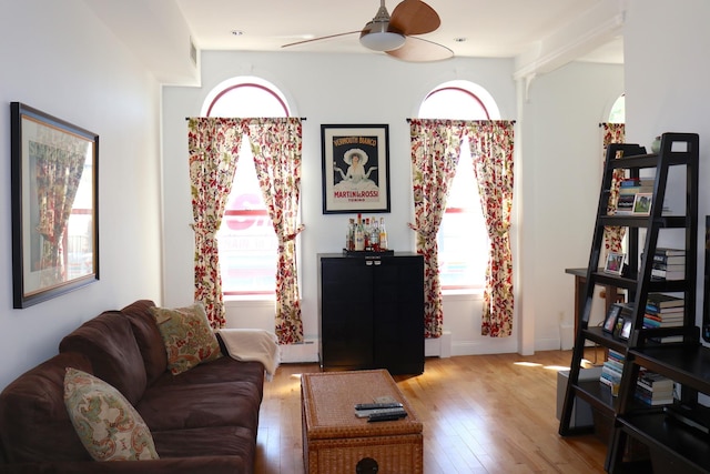 living room with baseboards, a ceiling fan, and light wood-style flooring