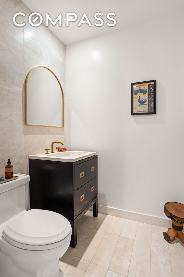 bathroom featuring toilet, tile walls, tile patterned flooring, and vanity