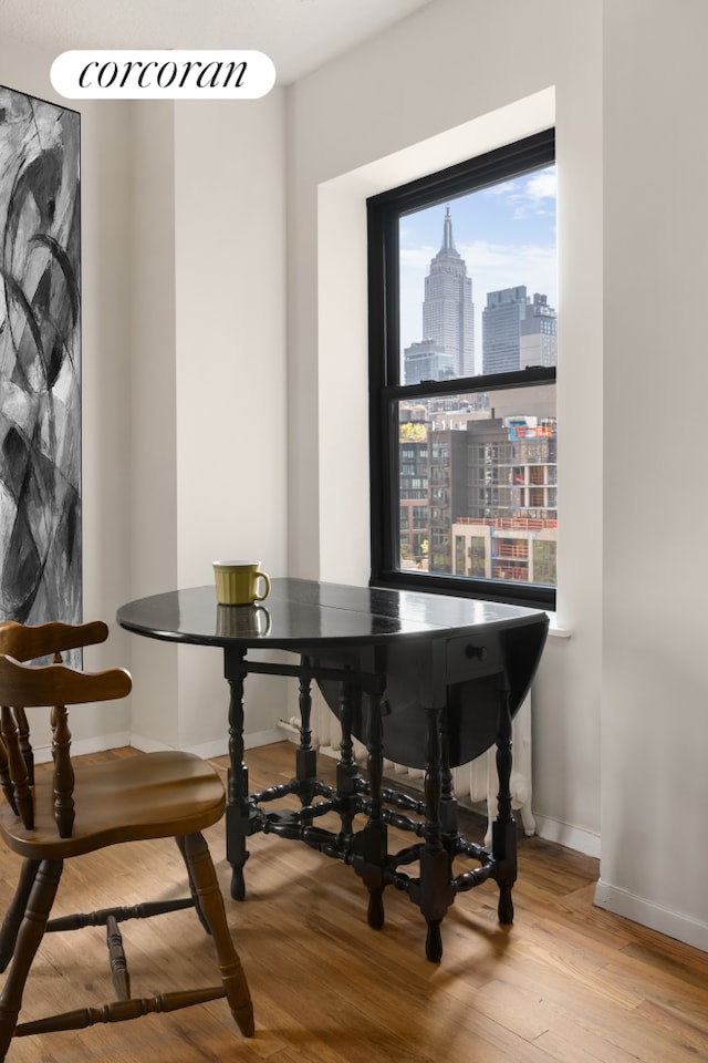 315 W 23rd St Unit 10F, New York City, NY 10011 - dining space with wood finished floors, baseboards, and a skyline view