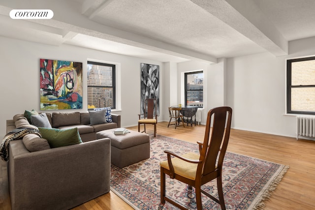 315 W 23rd St Unit 10F, New York City, NY 10011 - living area with radiator, beamed ceiling, light wood finished floors, baseboards, and a textured ceiling