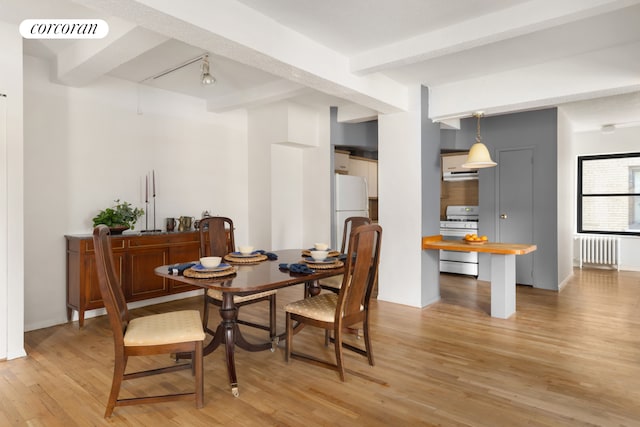 315 W 23rd St Unit 10F, New York City, NY 10011 - dining room featuring radiator, beam ceiling, and light wood-style flooring