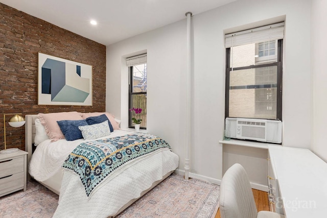 bedroom featuring wood finished floors, brick wall, baseboards, recessed lighting, and cooling unit