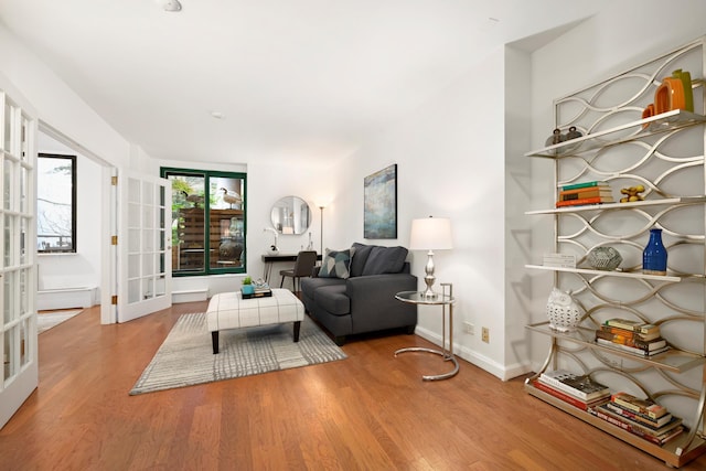 living area featuring french doors, baseboards, and wood finished floors