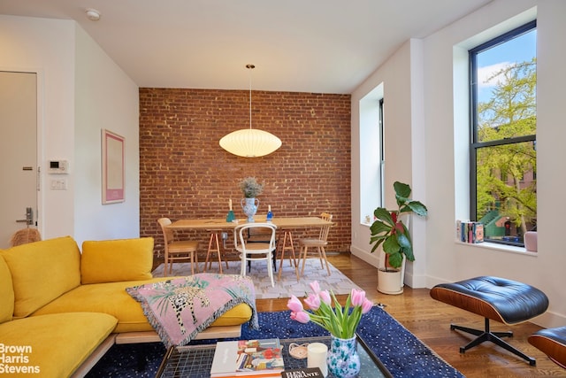 living room featuring baseboards, brick wall, and wood finished floors