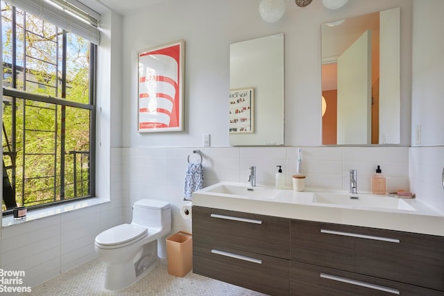 bathroom featuring tile walls, a healthy amount of sunlight, and a sink