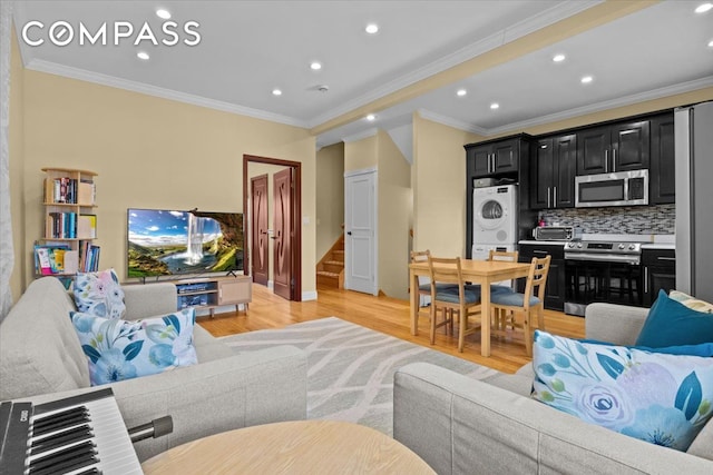 living area featuring recessed lighting, crown molding, light wood-style floors, and stacked washer and dryer