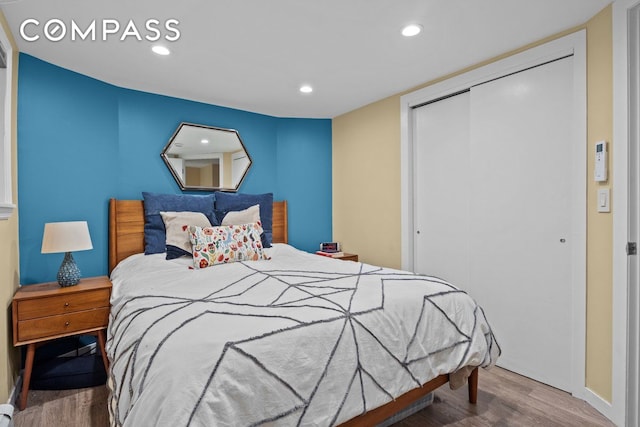 bedroom with a closet, recessed lighting, baseboards, and wood finished floors
