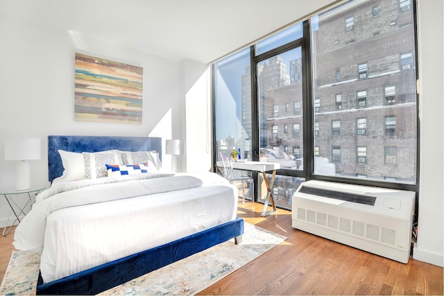 bedroom with floor to ceiling windows and wood finished floors