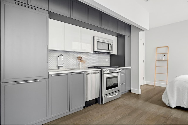 kitchen featuring appliances with stainless steel finishes, a sink, gray cabinetry, and light countertops