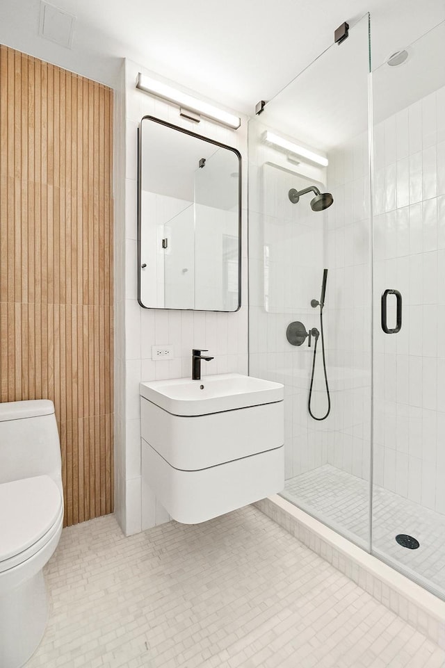 full bath featuring a stall shower, toilet, vanity, and tile walls