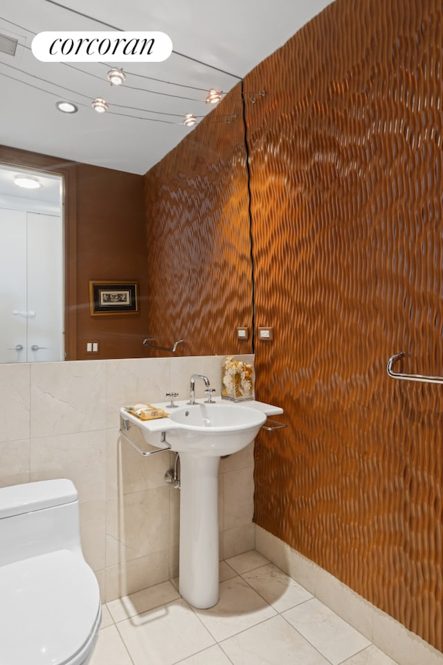 bathroom with toilet, tile walls, and tile patterned flooring