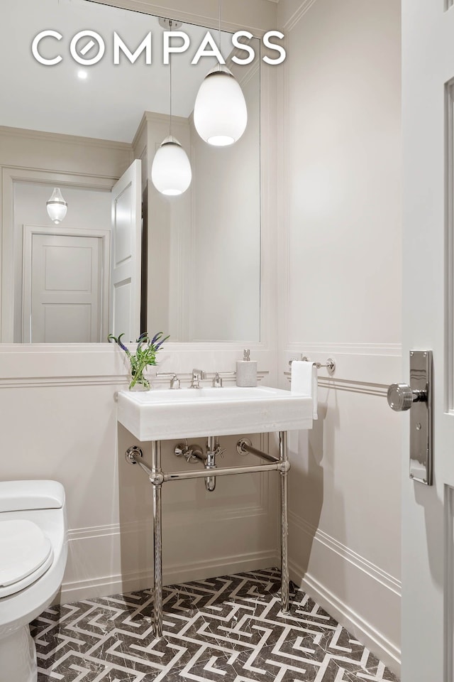 half bath with toilet, baseboards, and brick floor