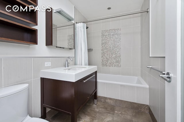 bathroom featuring tile walls, tiled shower / bath, vanity, and toilet