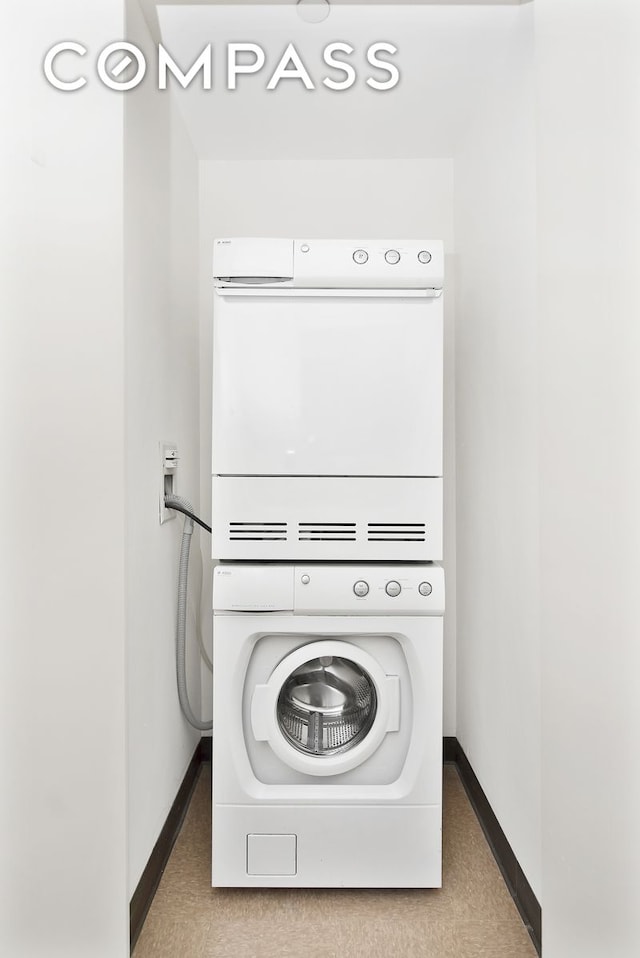 clothes washing area with baseboards and stacked washer and dryer
