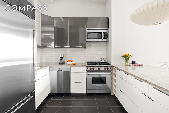 3 Hanover Sq Unit 7D, New York City, NY 10004 - kitchen with premium appliances, dark tile patterned flooring, decorative backsplash, modern cabinets, and white cabinetry