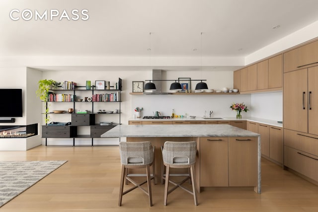 kitchen with a sink, open shelves, a breakfast bar, and light wood finished floors