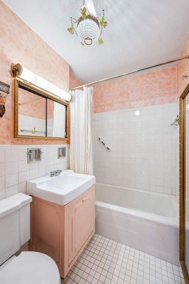 bathroom featuring vanity, toilet, tile patterned floors, tile walls, and shower / tub combo