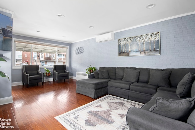 living room with brick wall, baseboards, hardwood / wood-style flooring, and a wall mounted air conditioner