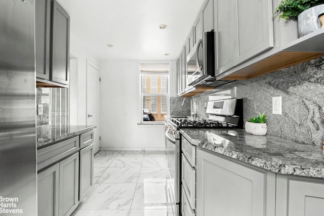 kitchen with gray cabinets, tasteful backsplash, stone countertops, marble finish floor, and stainless steel appliances