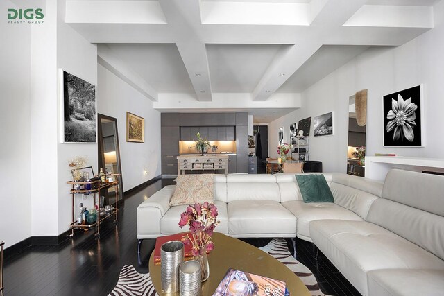 living room featuring baseboards, beamed ceiling, and wood finished floors