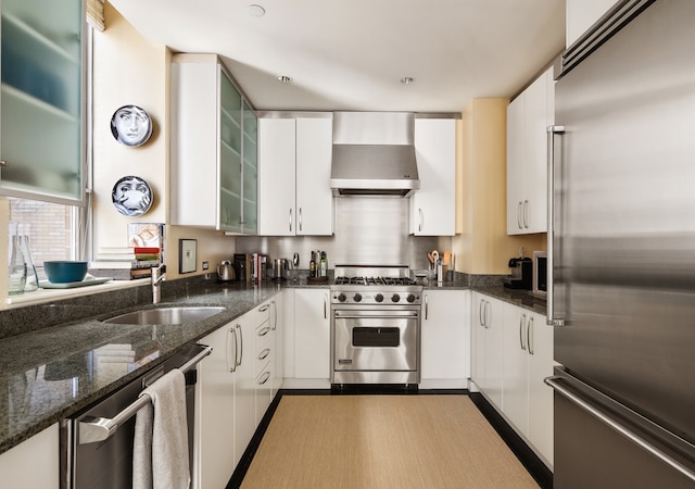 kitchen featuring a sink, high end appliances, wall chimney exhaust hood, and white cabinetry