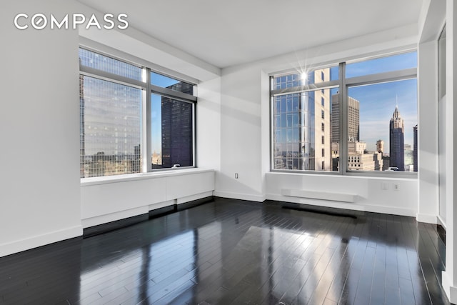 123 Washington St Unit 52F, New York City, NY 10006 - spare room with dark wood-style floors, baseboards, and a view of city