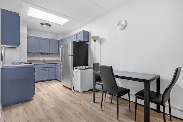 kitchen featuring blue cabinets, light wood finished floors, a skylight, and stainless steel appliances