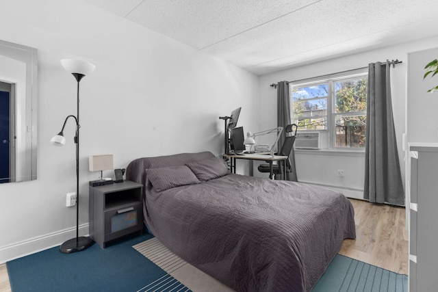 bedroom featuring baseboards, a textured ceiling, and wood finished floors