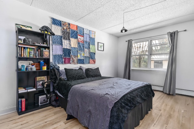 bedroom featuring baseboard heating and wood finished floors