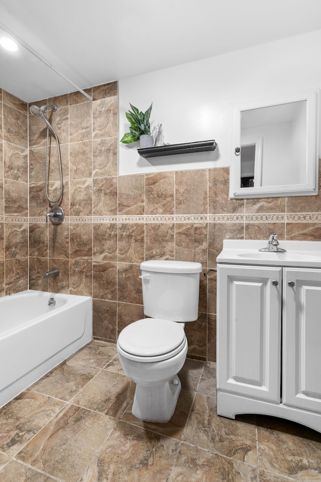 bathroom featuring tile walls, vanity, toilet, and bathing tub / shower combination