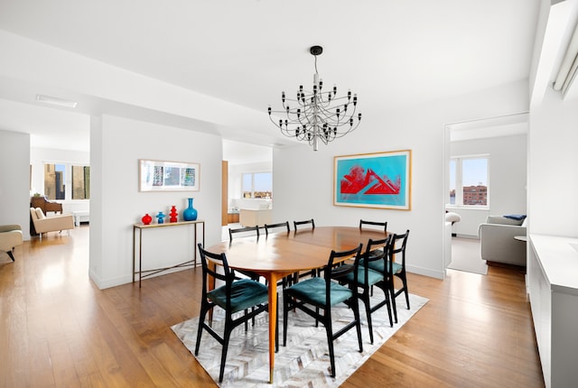 dining space featuring a healthy amount of sunlight, baseboards, light wood-type flooring, and a chandelier