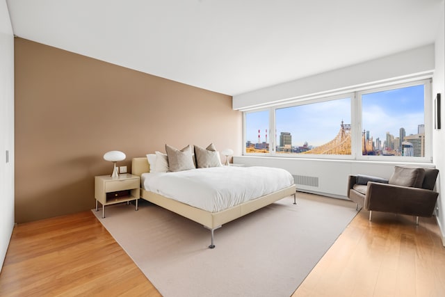 bedroom with a view of city and light wood-style flooring