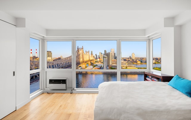 bedroom with a view of city, heating unit, a water view, and wood finished floors