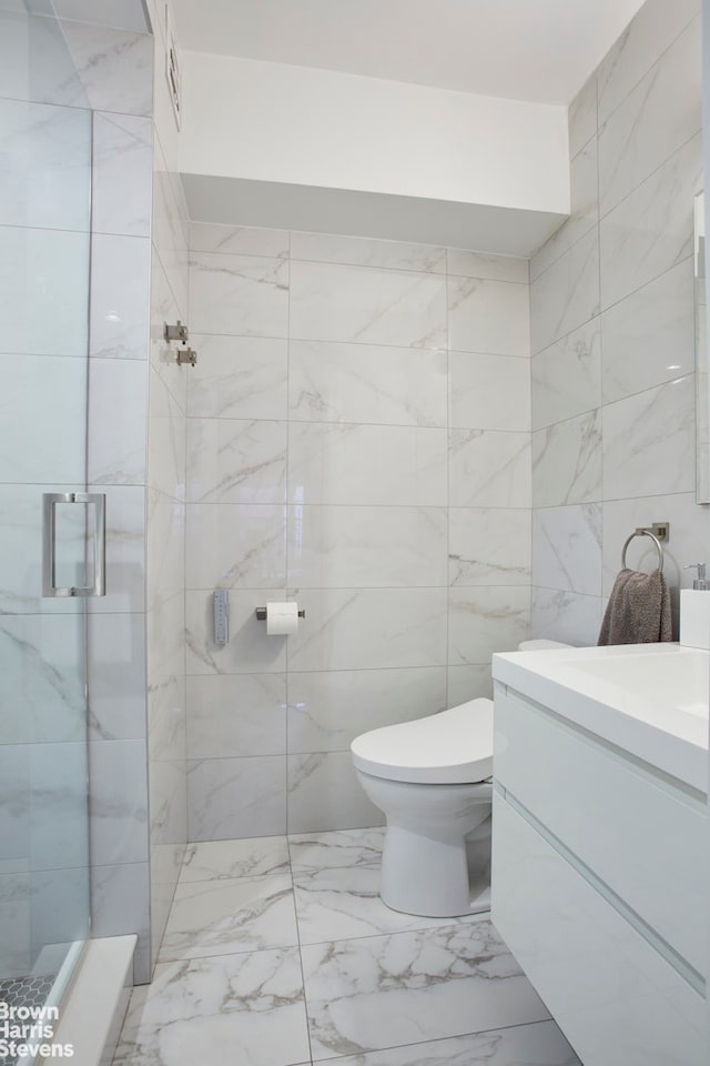 bathroom with vanity, marble finish floor, toilet, tile walls, and a shower stall