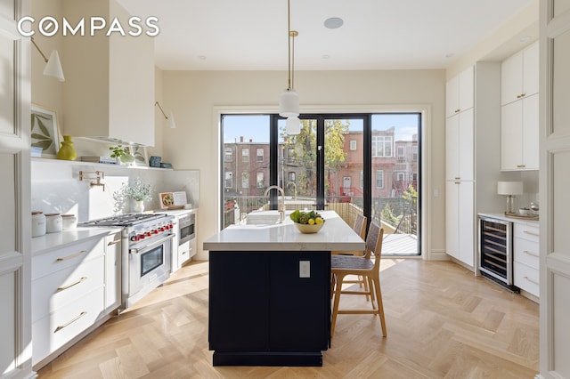 198 Madison St Unit Sf, New York City, NY 11216 - kitchen with wine cooler, stainless steel appliances, light countertops, white cabinets, and a kitchen island with sink