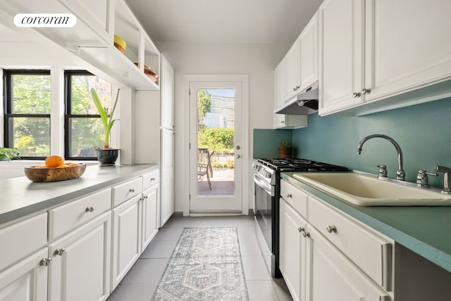 kitchen with light tile patterned flooring, a sink, stainless steel gas stove, white cabinetry, and under cabinet range hood