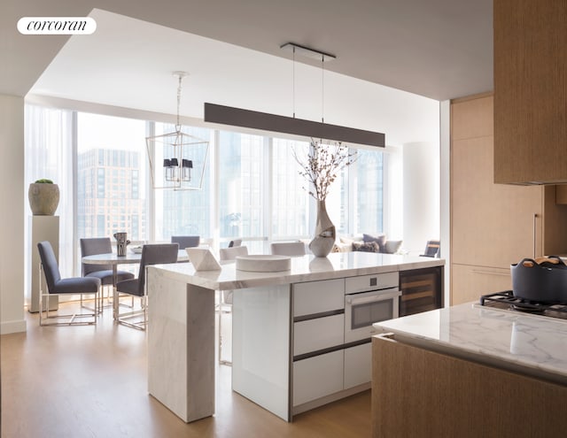 kitchen featuring white oven, a notable chandelier, light wood-type flooring, and a wealth of natural light