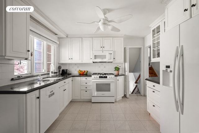kitchen with decorative backsplash, a ceiling fan, dark countertops, a sink, and white appliances