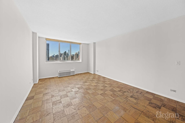 empty room featuring a textured ceiling, baseboards, and a wall mounted air conditioner